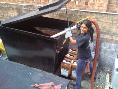 женщина собирает использованное растительное масло из мусорного бака